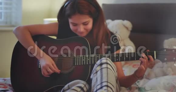 可爱的女士在她的卧室里弹吉他她很享受时间放学后休息一下然后开始视频的预览图