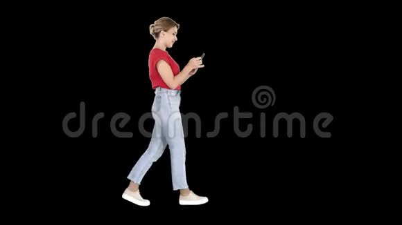 美丽的年轻女子在她的手机上行走和阅读短信视频的预览图