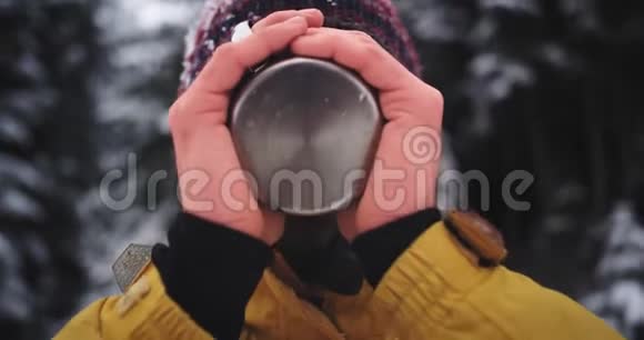 有魅力的微笑游客在山中央喝热茶的肖像冷冻手的细节视频的预览图