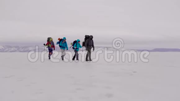 一群极端的旅行者在冬天的雪地上散步在山上徒步旅行四个人视频的预览图