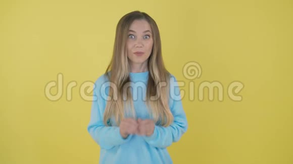 年轻而震惊的女人看着4K相机时被隔离在黄色背景下视频的预览图