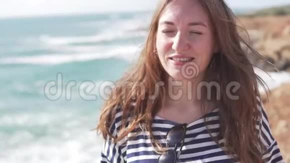一个女人站在海边看着镜头视频的预览图