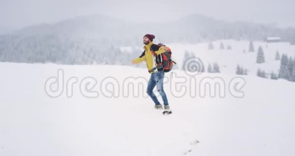 年轻的游客快乐地欣赏着大自然的一切美丽在一个冬天的雪山上他穿着视频的预览图