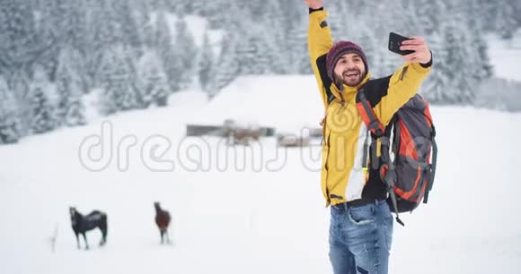 微笑的大青年游客在一个冬天的日子里在山中旅行他来到了一个乡村带着视频的预览图