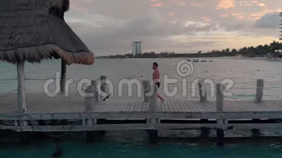 一个年轻的白种人在一个热带海滩度假胜地附近的码头上潜水视频的预览图