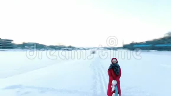 冬天穿着红色羽绒服的女孩在无人机旁飞来飞去女人会下雪视频的预览图