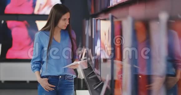 智能现代女性客户选择大型电视机在电子商店新的银幕时代视频的预览图