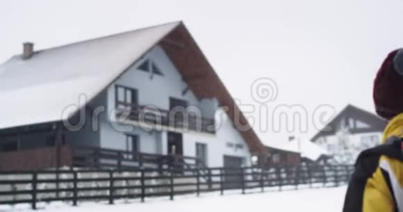 在下雪的冬日里一个背着一个大旅游包的游客来到了他的目的地一座山屋在视频的预览图