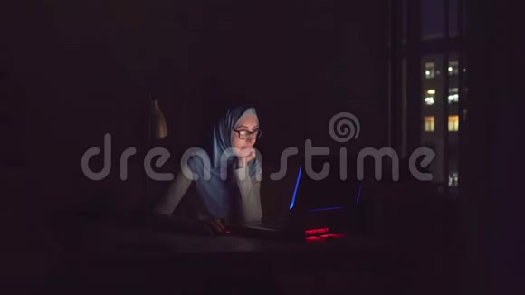 穆斯林女孩戴着眼镜戴着头巾带着笔记本在家里在网上暗查视频的预览图