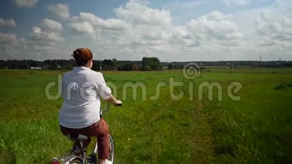女孩骑着自行车穿过绿色的田野视频的预览图