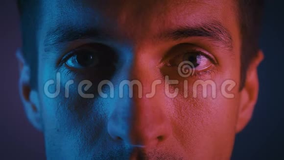 在多色霓虹灯中闭上男性的眼睛一个年轻人在晚会上穿着霓虹灯的肖像视频的预览图