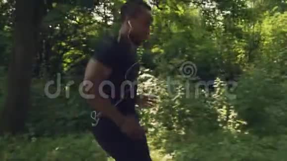 一个肌肉发达的非洲男人早晨穿过绿色森林视频的预览图