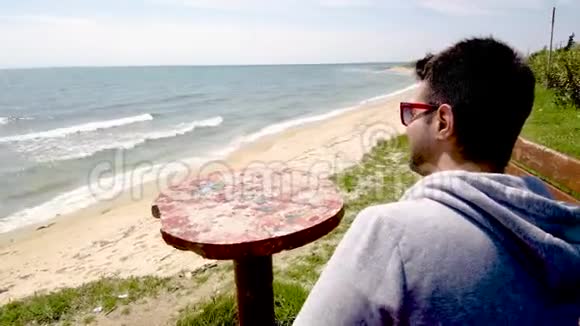 希腊哈尔基迪基一个年轻人坐在沙滩上看着大海一边打电话视频的预览图