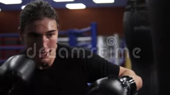 特写镜头确定侵略性的拳击手穿黑色T恤击中拳击梨一个愤怒的拳击手打了一拳视频的预览图