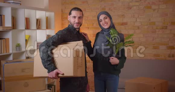 一对年轻开朗的穆斯林夫妇站在新买的公寓里看着摄像机开心地微笑的特写照片视频的预览图