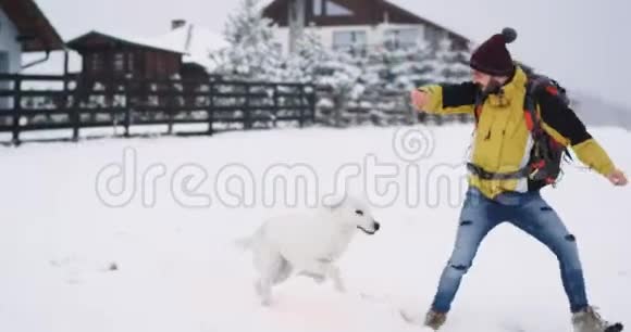 快乐的游客在山中和一只大白狗玩耍他在冬天用他的大橘子旅行视频的预览图