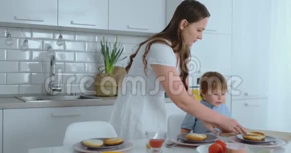 年轻的母亲帮助孩子在厨房里做汉堡视频的预览图