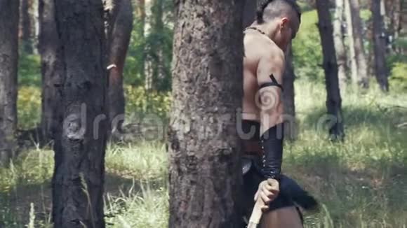 高大强壮的蛮族战士正拖着斧头在森林里行走视频的预览图