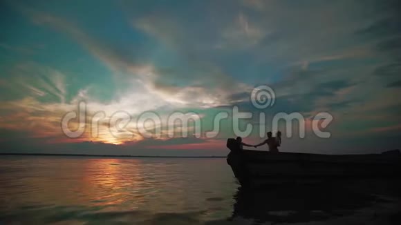 女人和男人握着手在日落时快乐地沿着湖边奔跑幼儿及家长剪报视频的预览图