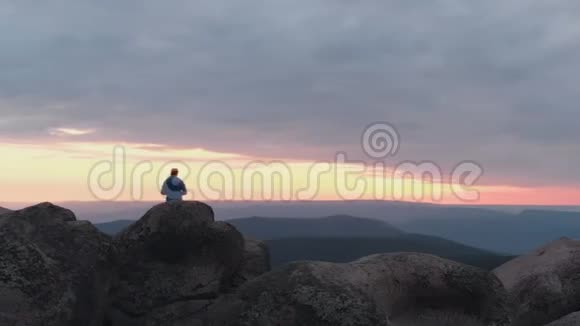 无人机拍摄的孤独男子站在山顶欣赏日落视频的预览图