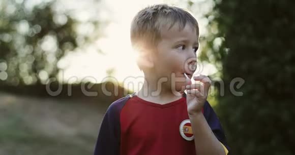 一个小男孩在户外吃棒棒糖的肖像视频的预览图