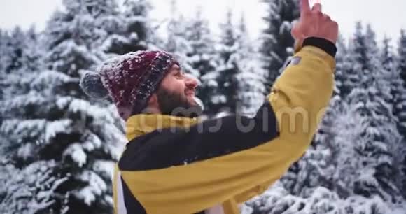 一位年轻的游客在冬天给一片雪林拍照他对他所看到的一切美景印象深刻视频的预览图