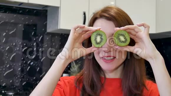 快乐兴奋的年轻女人在厨房准备食物之前玩成熟的猕猴桃积极的人类情感视频的预览图