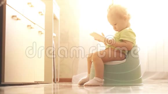 有趣的焦点宝宝坐在马桶上使用智能手机视频的预览图