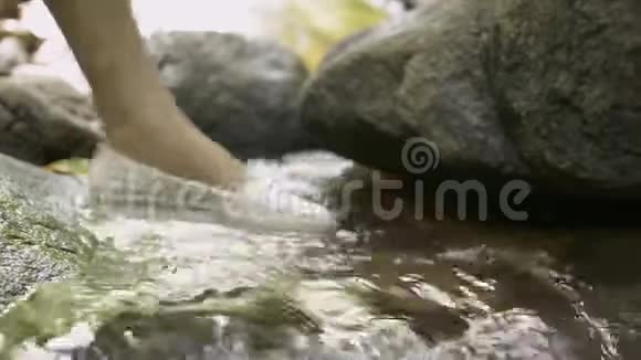 在热带丛林中的河流岩石上行走时把女人的腿收起来视频的预览图