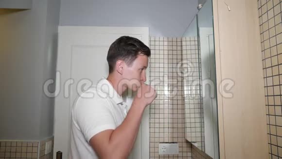 年轻人早上在浴室里刷牙看着镜子视频的预览图