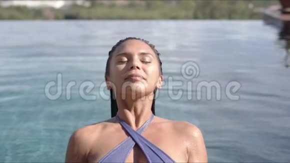 阳光下度假胜地游泳池里的漂亮女人视频的预览图