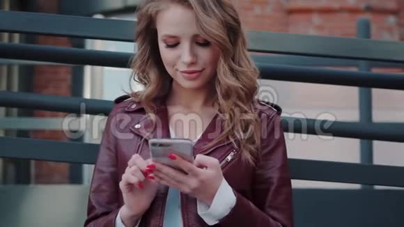 一个手里拿着手机的时髦年轻女人的肖像有魅力的女孩在智能手机上聊天视频的预览图