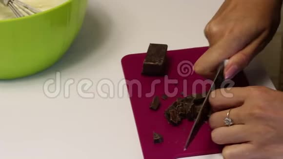 女人用黑巧克力做刨花用刀在切割板上做甜点视频的预览图