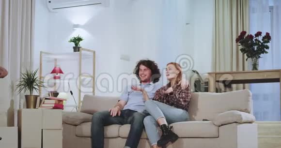 一对微笑而兴奋的夫妇在一个新公寓里度过了艰难的一天他们从电视上拿走了遥控器视频的预览图