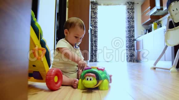 静态镜头可爱的七个月大的男孩在地板上玩教育玩具快乐的童年早期发展视频的预览图