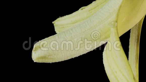 一根黄色的香蕉一张张开的皮肤挂在黑色的背景上视频的预览图