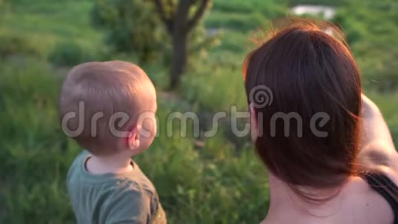快乐的年轻女子坐着和她的孩子玩在湖在日落在斯洛文尼亚视频的预览图