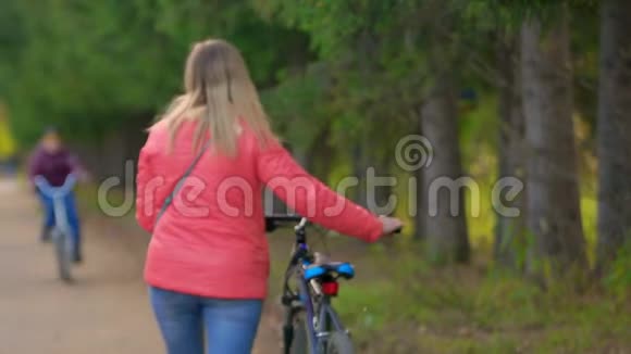 女人带着自行车在公园里散步她从摄像机旁走开视频的预览图