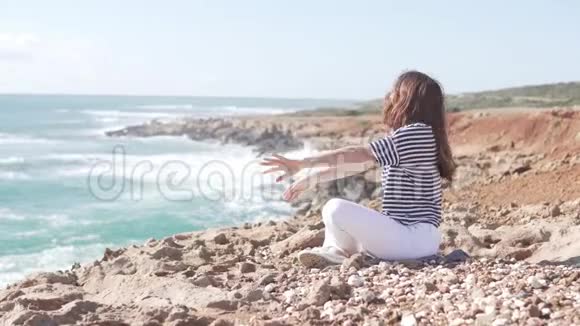 一位年轻女子坐在海边做体操视频的预览图