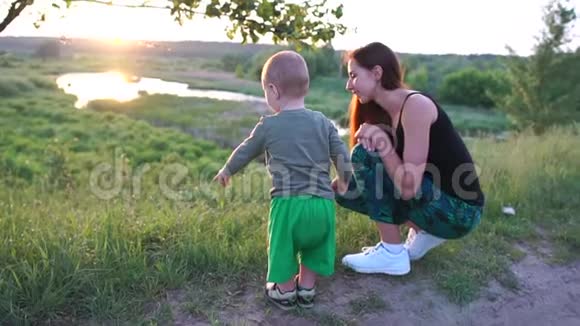 快乐的母亲坐在小湖边和她的孩子聊天日落时分在斯洛文尼亚视频的预览图