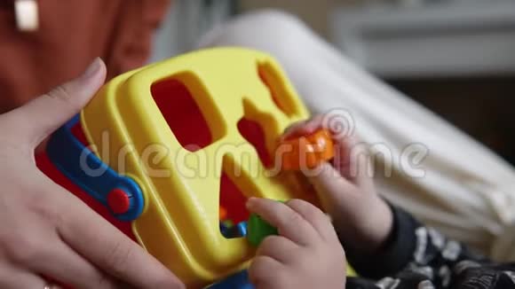 孩子和他妈妈玩一个多色玩具分类机双手合拢视频的预览图