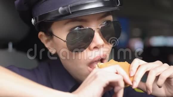 饥饿的亚洲巡警坐在警车上吃汉堡吃油腻的食物视频的预览图