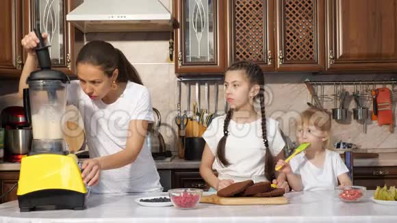 妈妈用搅拌机和她的两个女儿一起煮奶油做蛋糕视频的预览图