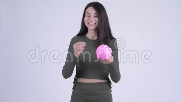 快乐的年轻美女在储蓄罐里插硬币开玩笑视频的预览图