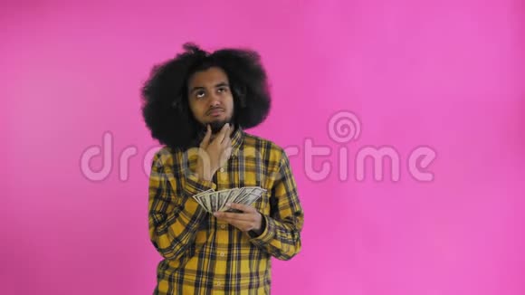 非裔美国人手里拿着钱想着紫色背景的东西视频的预览图