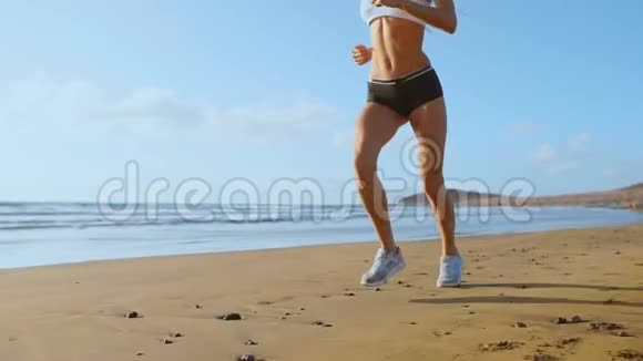 美丽的女人穿着运动短裤和t恤在海滩上奔跑沙滩上有白色的沙子和蓝色的海水视频的预览图