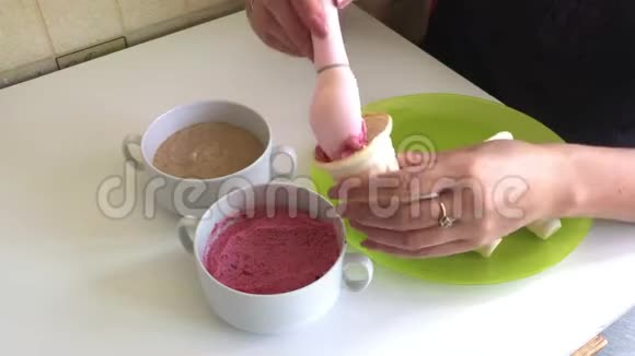 一个女人把草莓冰淇淋装满了喇叭用冰淇淋勺放在盘子上桌子上有集装箱和视频的预览图