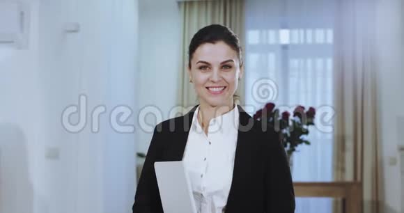 一位穿着休闲服的微笑女商人的肖像直视着摄像机露出一个大大的白色微笑和视频的预览图