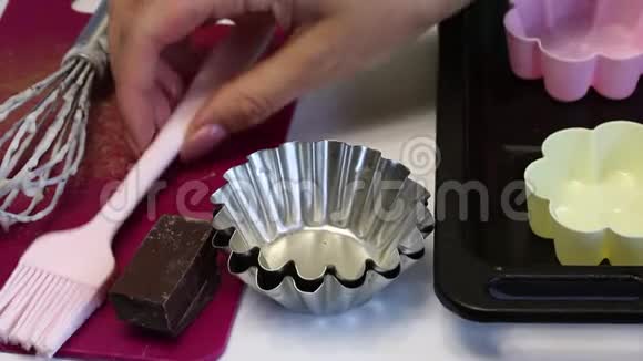 一个女人躺在桌子上做甜点的工具上硅胶和金属蛋糕烤盘搅拌器糕点刷做甜点视频的预览图