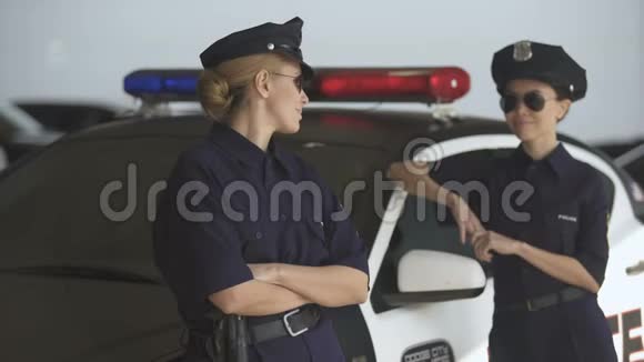 两名身穿警服的妇女站在巡逻车旁微笑着遵守法律和秩序视频的预览图